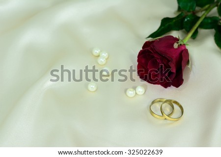 Pair of gold wedding rings  and red rose on silk background - gentle soft background for marriage