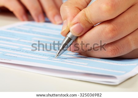 Hand with a pen writing. Accounting and finance background.