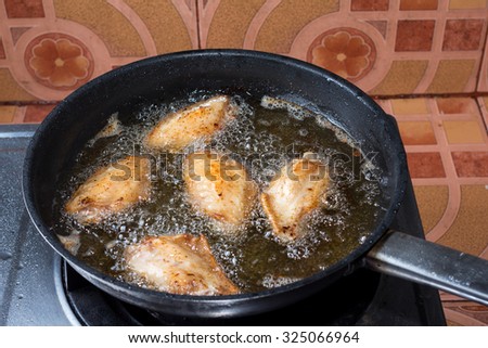 Chicken frying in a pan.