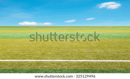 sport grass field against blue sky with clouds
