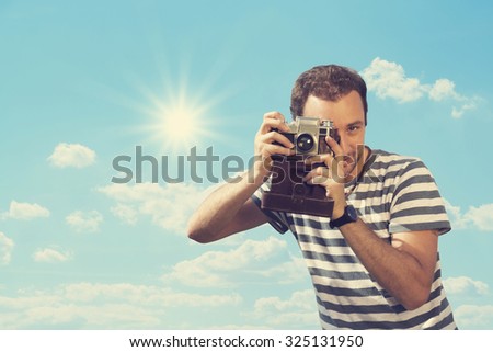 Young hipster man photographing with vintage camera.