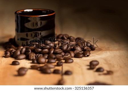 Espresso in black coffee cup with coffee beans on desk wood