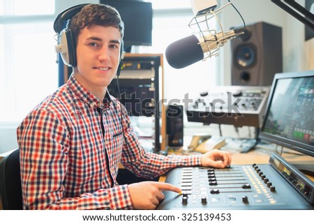 Portrait of radio host using sound mixer on table in studio