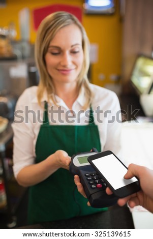 Female worker accepting payment from customer through NFC in bakery