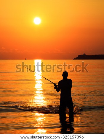 Fisherman silhouette at sunrise near the sea.