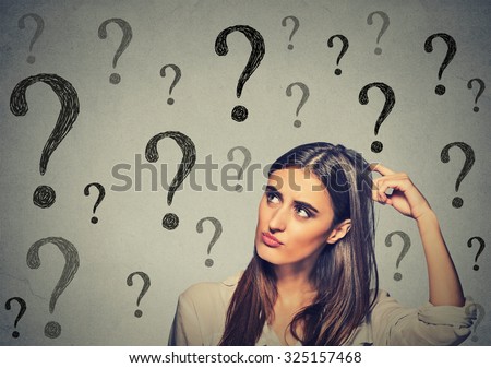 Portrait confused thinking young woman bewildered scratching her head seeks a solution looking up at many question marks isolated on gray wall background. Human face expression  Royalty-Free Stock Photo #325157468