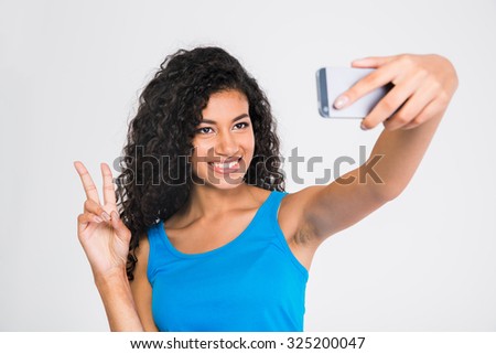 Portrait of a smiling afro american woman making selfie photo while showing two fingers sign isolated on a white background