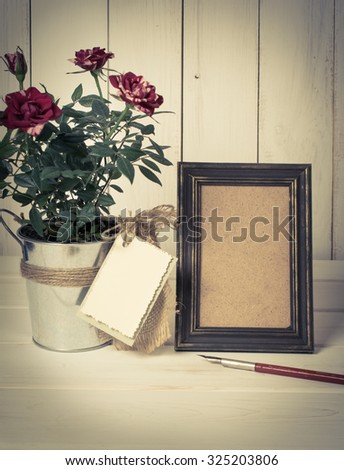 Retro photo frame and old pen with roses bouquet on wooden board in shabby chic style