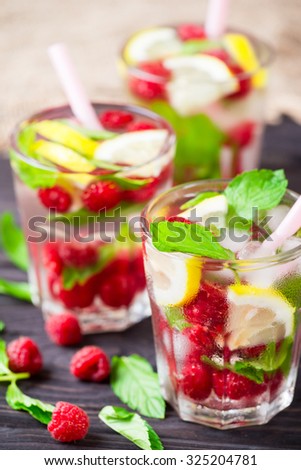 Lemonade with raspberry, lemon and mint in glass on rustic wooden background