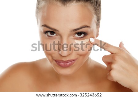 young woman apply concealer under the eye Royalty-Free Stock Photo #325243652