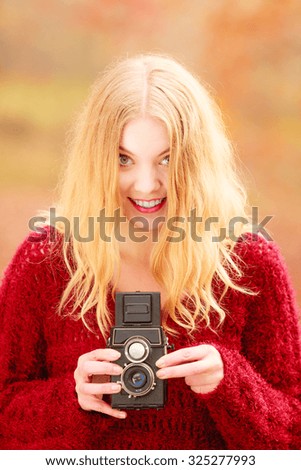 Portrait of pretty smiling woman in fall forest park with old vintage camera. Happy gorgeous young girl passionate photographer. Autumn winter photography.