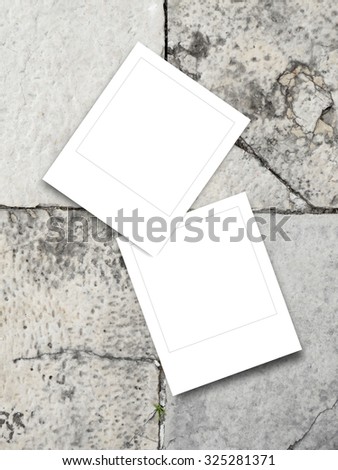Two blank square instant photo frames on concrete tiles
