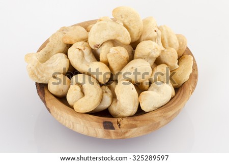 Roasted cashew nuts in wooden bowl on white background
