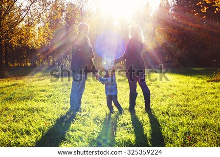 Picture of lovely family in Autumn Park, happy young parents with nice adorable son playing outdoors