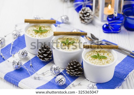 Rice Pudding with Cinnamon, New Year Ornaments in Blue Color, Pine cones and Candle