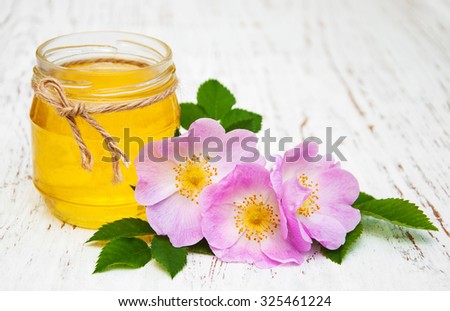 Honey and dog rose flowers on a old wooden background