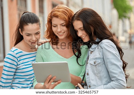 tourism, travel, leisure, holidays and friendship concept - smiling teenage girls with tablet pc computer and camera outdoors