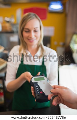 Female worker accepting payment from customer through credit card in bakery