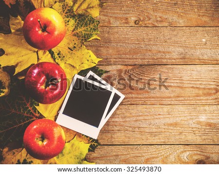 Autumn background with colorful leaves and apples on rustic wooden board. Creating fall season memories with retro photo cards of photo frames. Thanksgiving and Halloween holidays concept. Copyspace
