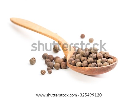 Aromatic allspice in wooden spoon. Isolated on white background. Shallow depth of field.