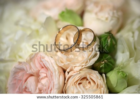 Closeup view of beautiful fresh soft wedding decorative bouquet of pink rose white peony and green flowers with two golden rings, horizontal picture