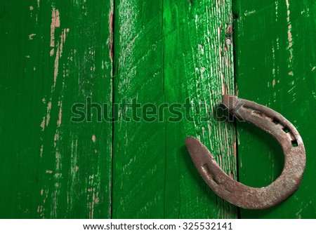 Old rusty horseshoe on vintage green wooden board