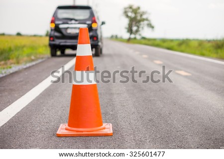 Orange rubber traffic cone on country road. It is used for warning to broken down car on country road, Thailand.