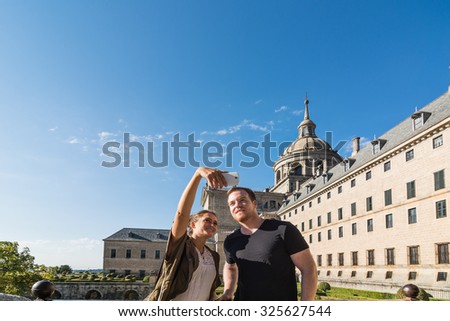 Young couple getting a selfie with Escorial Monastery at the bottom