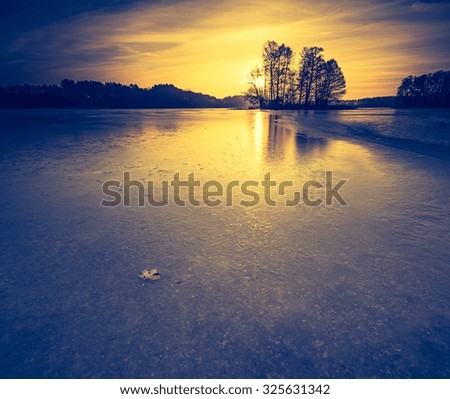 Beautiful landscape of frozen lake at sunrise. Photo with vintage mood effect.