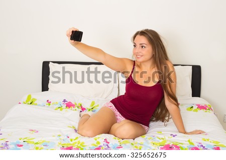 young woman taking a selfie in her bedroom