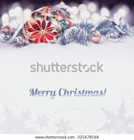 Christmas greeting card or border. Glass bauble with poinsettia, decorated branches of Christmas tree on snow. Toned image, isolated on gray, space for your text