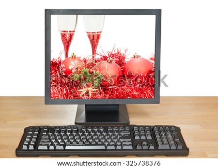 Christmas still life with red balls and glasses on screen of desktop PC isolated on white background