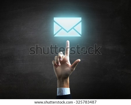 Businessman is indicating  a blue mail icon on black blackboard