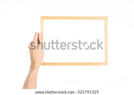 House decoration and Photo Frame topic: human hand holding a wooden picture frame isolated on a white background in the studio first-person view