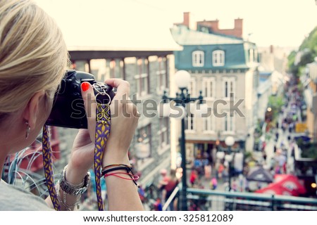 Young woman taking pictures on the busy rue  Petit Champlain in Quebec City, Canada. North American, adventure, travel vacation, photography, outdoors and life style concept