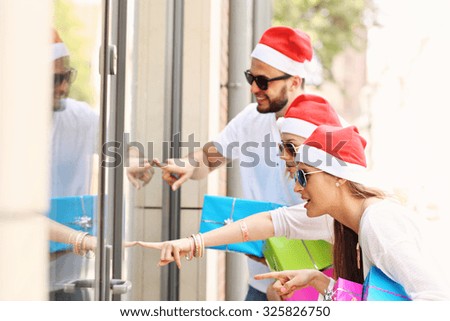 A picture of group of friends in Santa's hats sitting in the city with presents