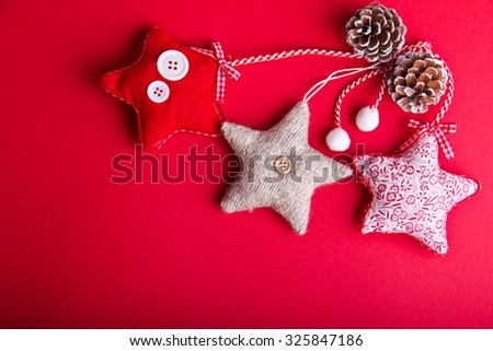 Three decorative stars and few pine cones on hot red background. Christmas and New Year theme. Place for your text, wishes, logo.