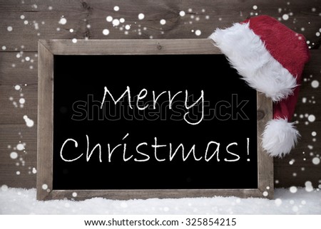 Gray Blackboard With Red Santa Hat On White Snow. English Text Merry Christmas. Snowy Atmosphere With Snowflakes. Christmas Decoration With Brown Vintage Wooden Background. Black And White