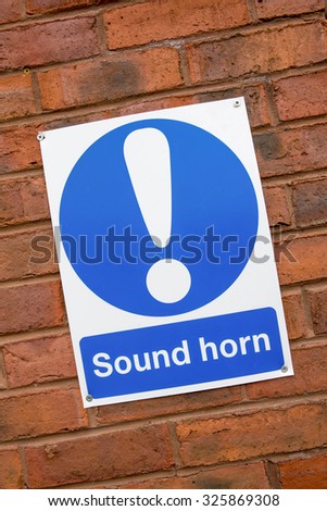 Traffic Sign Urging People to Sound their Horn against a Brick Wall Background