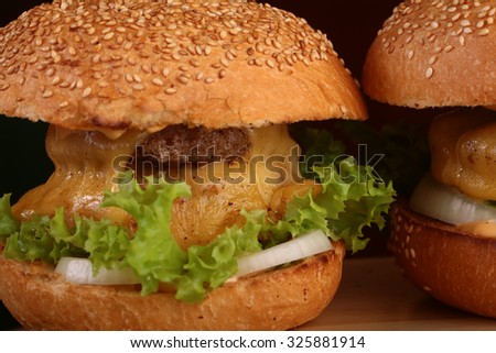 One big tasty appetizing fresh burger of green lettuce red tomato cheese and bacon slice meat cutlet and white bread bun with sesame seeds closeup, horizontal picture