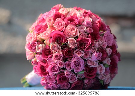 Closeup of one big beautiful colorful soft aroma fresh wedding bouquet of many pink and purple rose flowers lying sunny day outdoor on natural background, horizontal picture