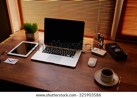 Mock up of freelancer desktop with accessories and work tools, laptop computer and digital tablet with copy space screen, mouse, plant pot, cup of coffee, empty touch pad, business person workstation