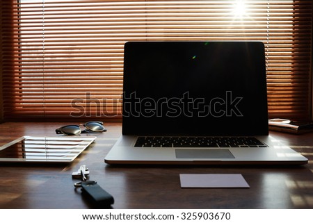 Mock up of freelance desktop with accessories and distance work tools, blank screen laptop computer and tablet, business workspace in home or office, net-book with touch pad lying on a wooden table 
