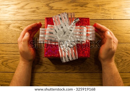 A man is sitting at a table and is holding red gift box