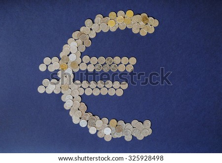 Euro sign from the coins on blue background. Creative art and money concept. Business and finance.
