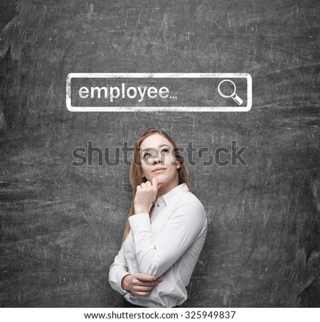 A beautiful recruiter by holding her chin is looking for new employees in the Internet. Internet concept of search available candidates. Black chalk board on the background.
