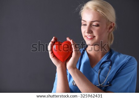 Doctor with stethoscope holding heart, isolated on gray background