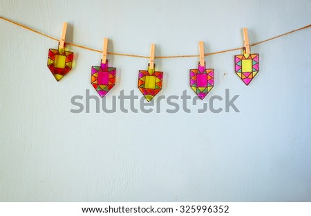 image of jewish holiday Hanukkah with Stained-glass colorful dreidels (spinning top) hanging on a rope over wooden background
