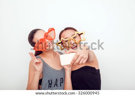 Asian girls in the funny sunglasses. They pose, grimace and look at the camera. Hair removed. The skin is clean. They make a picture on the phone.