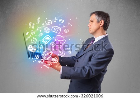 Middle aged businessman holding notebook with colorful hand drawn multimedia icons 